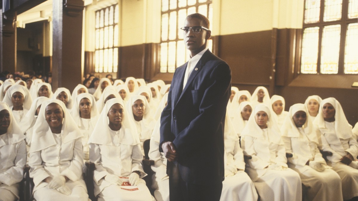 Malcolm X surrounded by women listening to his speech.