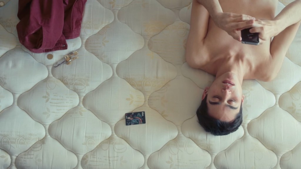 Santiago laying on an empty mattress looking at his phone in A Few Feet Away.