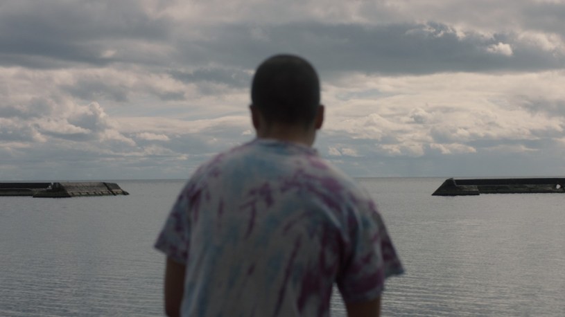 Z looking out to a body of water in Really Happy Someday.