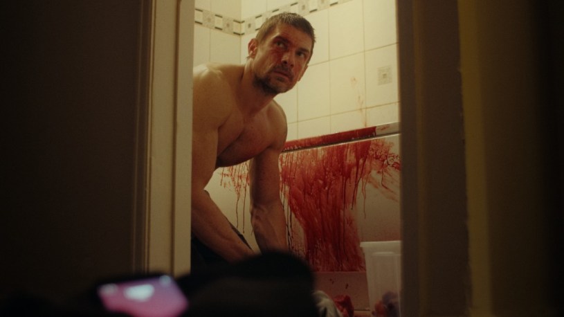 A bloodied Sion kneeling over a bath in Protein.