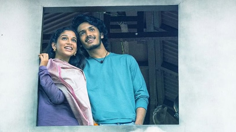 The two lead characters sat by a window ledge in Band Melam.